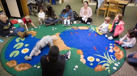 Adults and young children sitting in a circle listening to a story